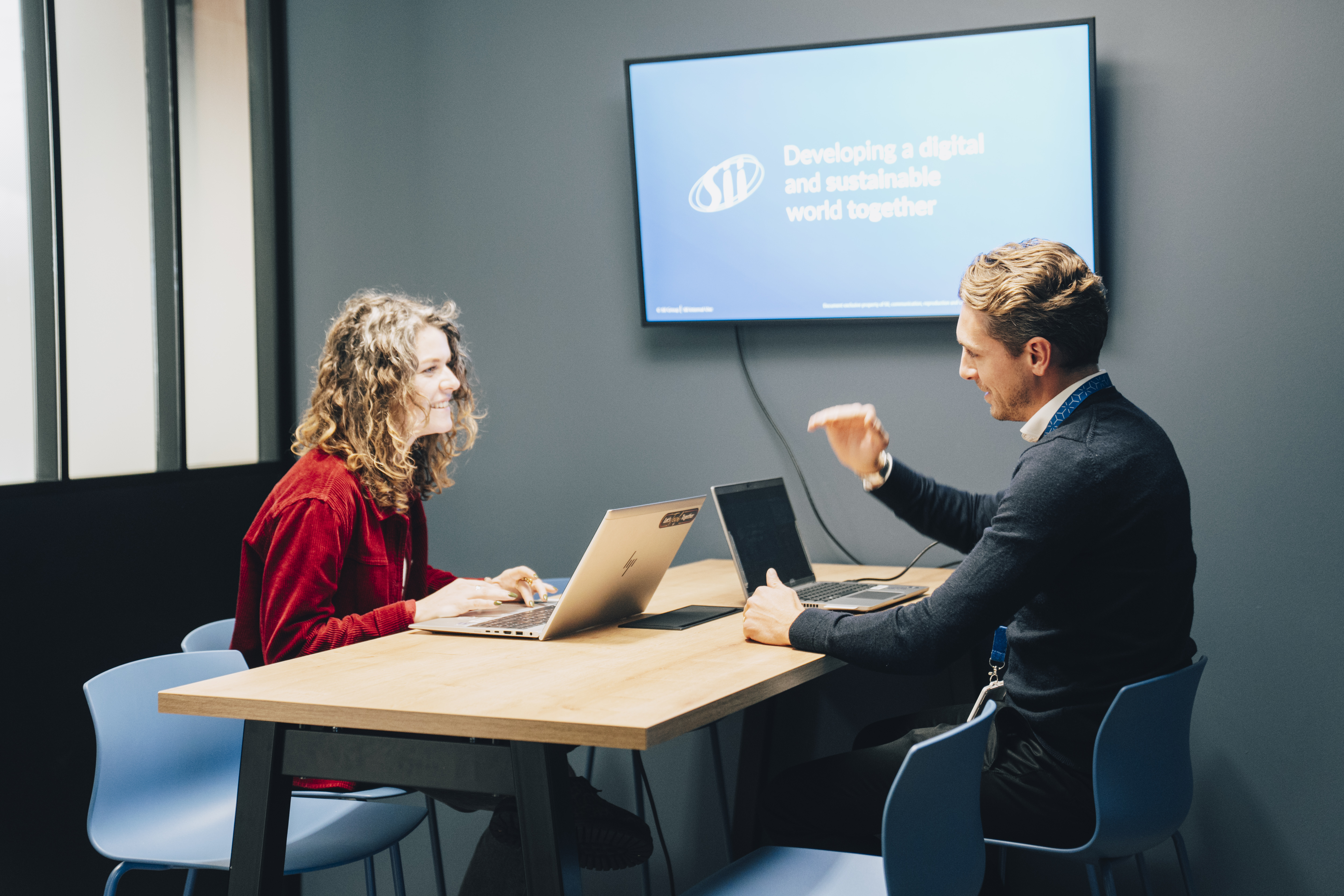 Deux collaborateurs dans un bureau, travaillant devant un écran avec le logo SII visible.